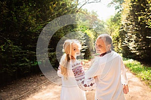 A young couple in a traditional Ukrainian clothing whith bouquet enjoy the sunny day at Stryisky Park in Lviv. Backview