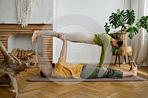 Young couple training yoga in pair doing acrobatic plank together