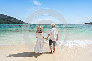 Young couple traveler relaxing and enjoying at beautiful tropical white sand beach with wave foam and transparent sea, Summer