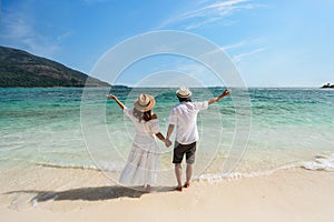 Young couple traveler relaxing and enjoying at beautiful tropical white sand beach with wave foam and transparent sea, Summer