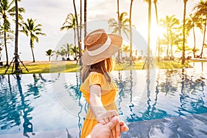 Young couple traveler relaxing and enjoying the sunset by a tropical resort pool while traveling for summer vacation