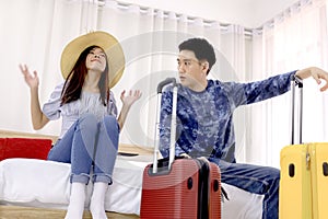 Young couple traveler sitting on bed in hotel room on summer vacation. Couple sitting on bed near window enjoying free Time in