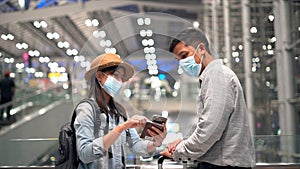 Young  Couple traveler sitting and relax in the terminal aiith suitcase standing on the moving walkway while using smartphone.