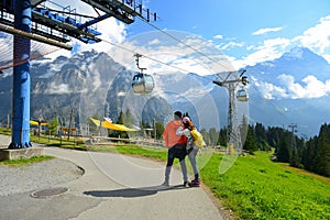 Young couple of travelers enjoying a mountains view in the summer at cabel car station ,Grindelwald Switzerland, photo