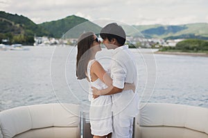 Young couple is traveling on a yacht in the Indian ocean. Man and a woman stand on the edge of the boat and kiss.