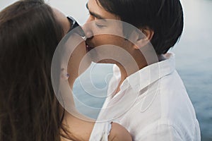 Young couple is traveling on a yacht in the Indian ocean. Man and a woman stand on the edge of the boat and kiss.