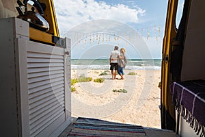 Young couple travelling by campervan along the seaside and chilling out at the beach