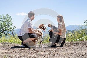 young couple travelling with dogs at the mountains, St.Bernard dog and yourkshire terrier