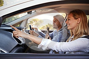 Young couple on a trip in a car navigating with a smartphone