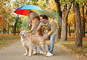 Young couple with umbrella and dog walking