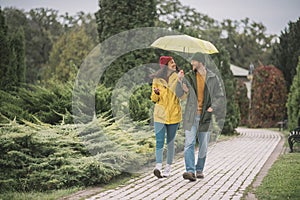 Young couple under yellow umbrela looking happy