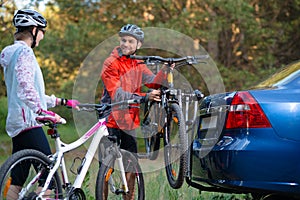 Young Couple Unmounting Mountain Bikes from Bike Rack on the Car. Adventure and Family Travel Concept.