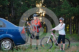 Young Couple Unmounting Mountain Bikes from Bike Rack on the Car. Adventure and Family Travel Concept.