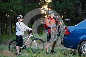 Young Couple Unmounting Mountain Bikes from Bike Rack on the Car. Adventure and Family Travel Concept.