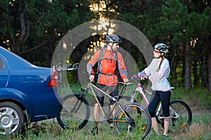 Young Couple Unmounting Mountain Bikes from Bike Rack on the Car. Adventure and Family Travel Concept.