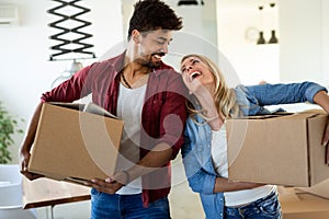 Young couple unpacking cardboard boxes at new home moving in concept