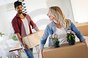 Young couple unpacking cardboard boxes at new home moving in concept