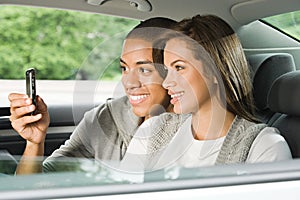 Young couple using a cellular phone in car