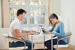 Young couple using digital tablet and laptop