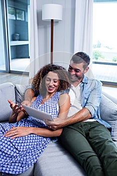 Young couple using a digital tablet on sofa