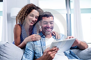 Young couple using a digital tablet on sofa