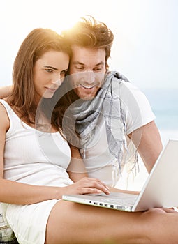 Young couple using laptop on the beach