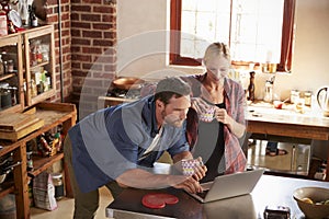 Young couple using laptop computer in kitchen, high angle