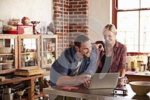 Young couple using laptop computer in kitchen, high angle