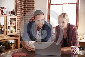 Young couple using a laptop in kitchen, close up, front view