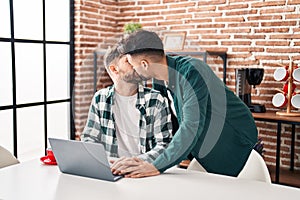 Young couple using laptop sitting on table at home