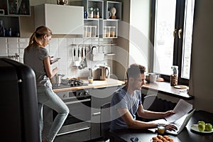Young couple using laptop and smartphone in the kitchen