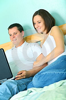 Young Couple Using Laptop On Their Bed