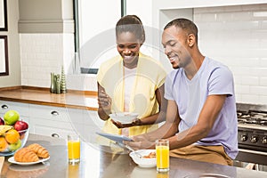 Young couple using tablet at breakfast