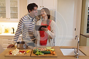 Young couple using tablet computer while cooking