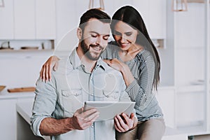 Young Couple Using Tablet PC in White Kitchen.