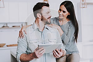 Young Couple Using Tablet PC in White Kitchen.