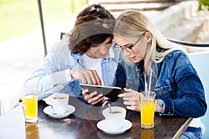 Young couple using tablet while sitting together at cafe