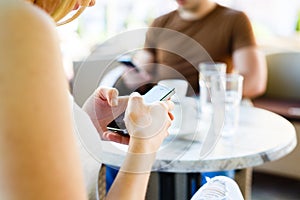 Young couple using their mobile phones while sitting at cafe