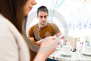 Young couple using their mobile phones while sitting at cafe