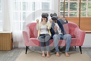 young couple using virtual reality headset playing game in living room at home