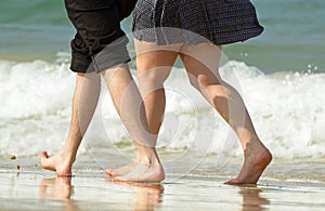 Young couple on vacation walking along waters edge of ocean