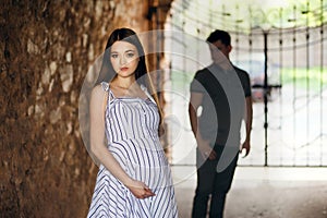 Young couple, very fashionable pregnant girl, couple in love in stone tunnel