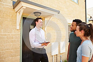 Young couple viewing a house with male real estate agent