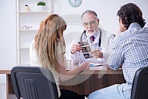 Young couple visiting old male doctor