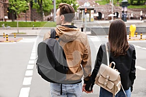 Young couple waiting to cross street, back view. Traffic rules and regulations