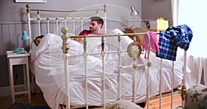 Young Couple Waking Up In Bed And Using Digital Devices