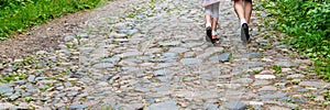 Young couple walk along old rural road with rocks and grass