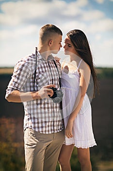 Young couple on a walk. Girl and guy lovingly look at each other on a sunny summer day on the street