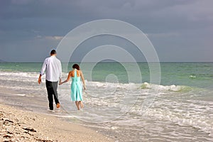 Young couple walking along bonita beach as sunsets photo