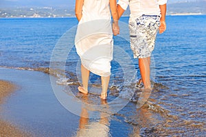 Young couple walking along lonely beach at sunset